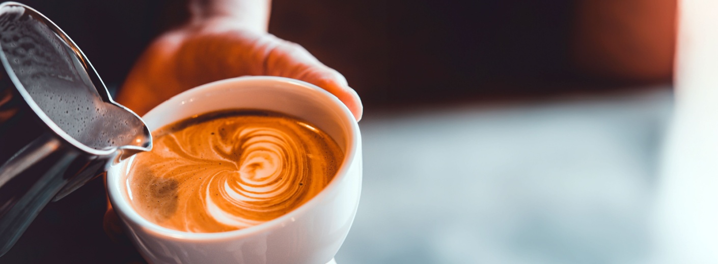 Person pouring cream into a coffee cup