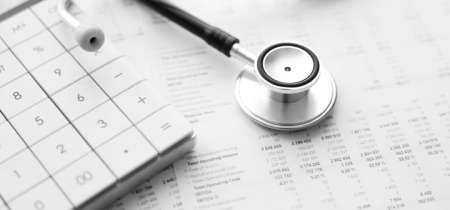 A stethoscope and calculator laying on top of paper.