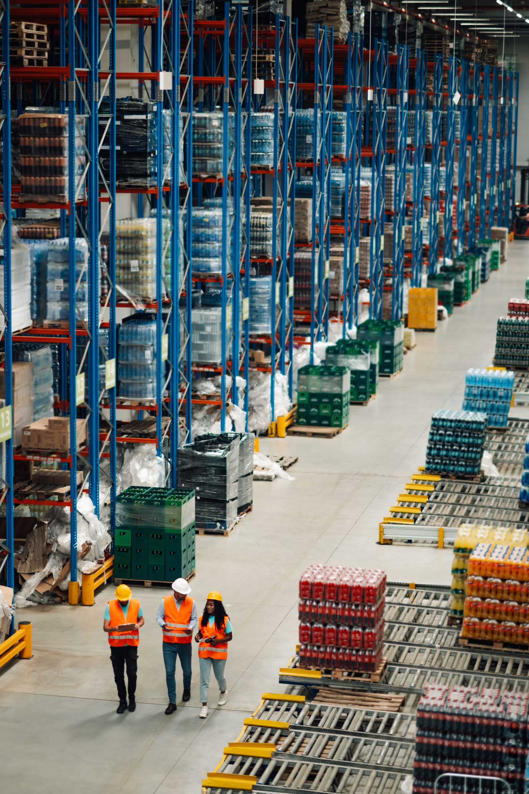 Three,Warehouse,Workers,In,Safety,Vests,And,Helmets,Are,Walking